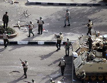Army soldiers fire their rifles in the air as they try to contain protesters outside the National Museum near Tahrir square in Cairo