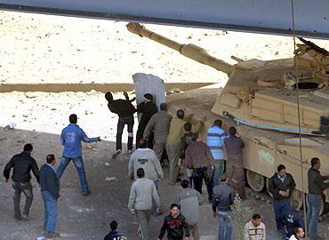 Pro-government protesters take cover behind an army tank during clashes with anti-government protesters outside the National Museum near Tahrir square