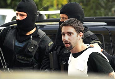 Policemen escort a terror suspect in Athens, who is charged with participating in a terrorist group and with illegal possession of explosives and weapons