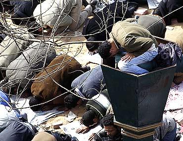 An anti-government protester on top of a lamppost prays during Friday prayers at Tahrir Square in Cairo