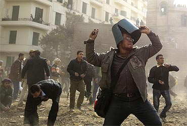 An opposition demonstrator throws a rock during rioting with pro-Mubarak supporters near Tahrir Square in Cairo