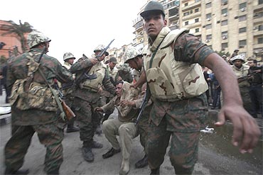 A pro-Mubarak supporter apprehended by opposition demonstrators is led away by the army during rioting near Tahrir Square in Cairo