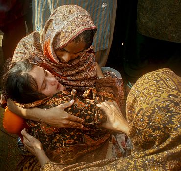 Family members comfort the sister of Shumaila, who committed suicide after her husband was killed