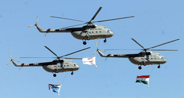 Indian Air Force helicopters fly before the start of display at Aero India 2011