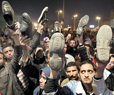 Anti-government protesters in Cairo's Tahrir Square wave shoes in dismay as President Hosni Mubarak speaks to the nation