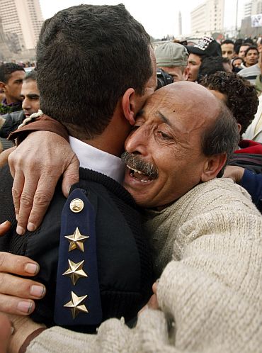 An Egyptian policeman is hugged by an opposition supporter in Tahrir Square