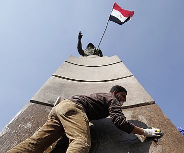 A man cleans the base of the statue of Egyptian Army General Abdul Moneim Riyad at Tahrir Square