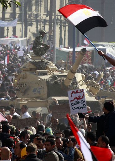 An Egyptian soldier atop a tank watches opposition supporters during a huge rally