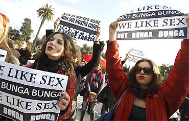Women hold placards during a demonstration against Berlusconi
