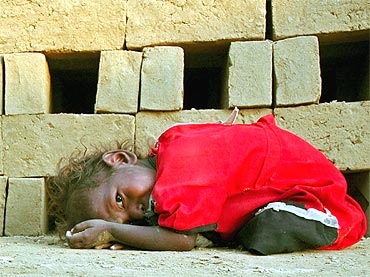 A child of a brick kiln worker rests at a brick factory in Gadopur village near Allahabad