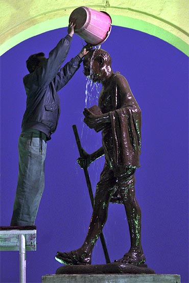 A worker cleans a statue of Mahatma Gandhi in Lucknow