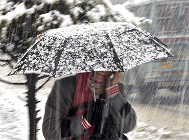 A Kashmiri woman carries an umbrella during snowfall in Srinagar