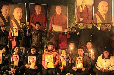 Tibetan exiles hold portraits of Karmapa Lama during a candlelight vigil in New Delhi