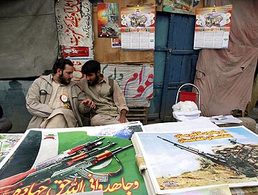 Supporters of Jamate-e-Islami sit next to posters and materials about Jihad in Peshawar