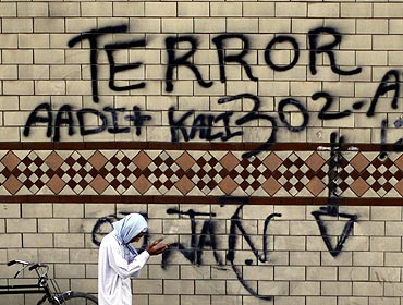 A man prays, next to graffiti painted road-side, during an anti-Taliban rally in Rawalpindi