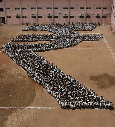 Students make a formation of the new symbol of the Indian rupee at a school in Chennai