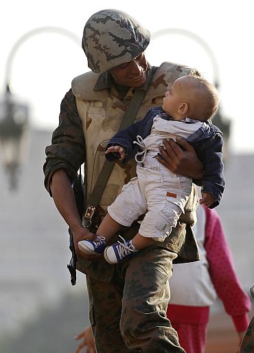 An Egyptian soldier holds a baby on top of his tank as he poses for photographs inside Tahrir Square