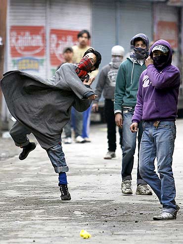 A Kashmiri protester throws stones at policemen