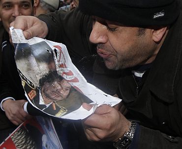 A demonstrator spits at a picture of Libya's Muammar Gaddafi
