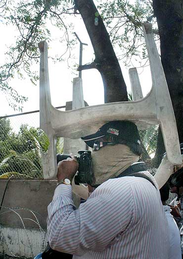 A photojournalist covers his head with a chair to protect himself while covering the protests in Hyderabad on Tuesday