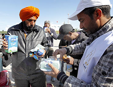 Indians fleeing unrest in Libya receive food and drinks after crossing the border into Tunisia