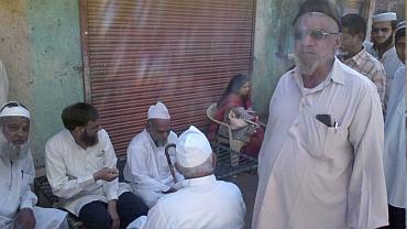 Syed Umerjee sits with his neighbours at his home near Godhra