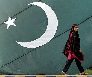 A woman walks past a Pakistani flag