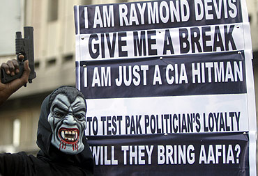 A supporter of a political party poses with a mask and toy gun during a protest against Davis