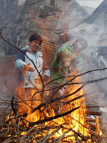 Kashmiri people warm their hands at a fire on a cold day in Srinagar