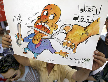 A protester holds up a cartoon sign that reads 'Don't kill the truth' during a protest at Baghdad