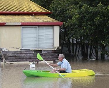 Christopher Roth rows down a flooded street in Bundaberg, affected by floods in Queensland