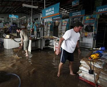 Workers of a hardware store start to clean up after being affected by flooded waters in Bundaberg, Queensland