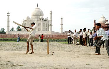 Children play cricket on the banks of river Yamuna, behind the Taj Mahal