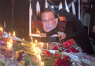 A woman lights a candle next to an image of the governor of Punjab Salman Taseer near the site of his assassination, in Islamabad