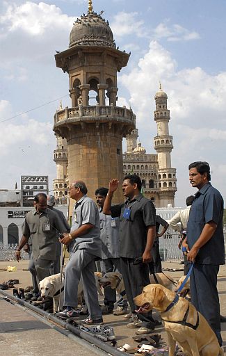Policemen use sniffer dogs to inspect the blast site