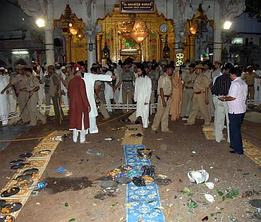 Security personnel and onlookers stand at the site of a bomb blast in Ajmer