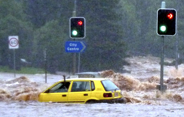 A passenger in a car waves for assistance as a flash flood sweeps across an intersection in Toowoomba, 105 km west of Brisbane