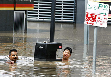 Shopkeepers salvage a coffee machine from their flooded shop in the Brisbane suburb of Milton