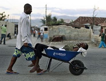 A Haitian with symptoms of cholera is transported in a wheelbarrow in the slums of Cite-Soleil in Port-au-Prince