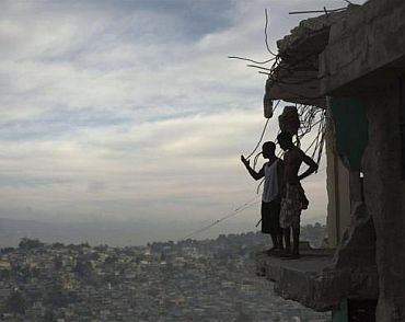 Orich Florestal (Left), 24 and Rosemond Altidon, 22, stand on the edge of their partially destroyed apartment of Port-au-Prince
