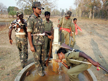 Security personnel drink water while patrolling a forest area in Chhattisgarh