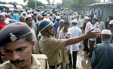 Policemen control a crowd gathered at a blast site outside a mosque in Malegaon