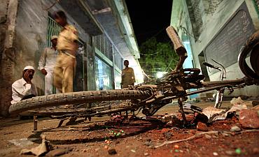 People walk past a damaged bicycle lying at a blast site inside a mosque in Malegaon