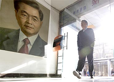 A man walks past a portrait of China's President Hu Jintao by artist Ye Zhifu outside a gallery in Beijing on Tuesday