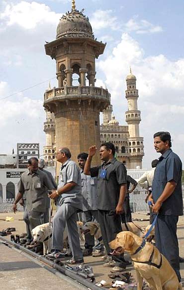 Policemen use sniffer dogs to inspect the site of a bomb blast at Mecca Masjid