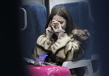 A woman cries while talking on the phone to an acquaintance who is at Domodedovo airport