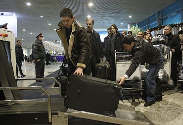 People entering Moscow's Domodedovo airport stand in line as they prepare to pass their belongings