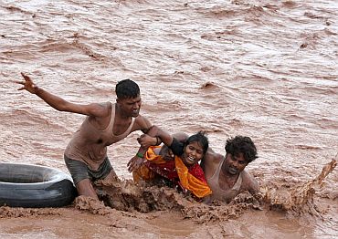 Rescuers help a woman to move a safer place from flooded Ghaghar river after heavy rains in Punchkula in the northern Indian state of Haryana September 8, 2010
