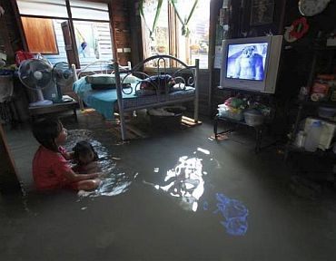 Residents watch television at their flooded house in Bangkok October 25, 2010