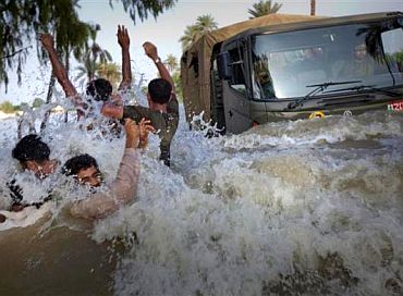Residents being evacuated through flood waters dodge an army truck carrying relief supplies for flood victims in Pakistan's Muzaffargarh district in Punjab province August 11, 2010